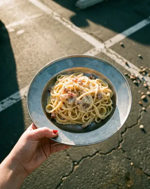 Spaghetti carbonara on a steel plate in the evening sun