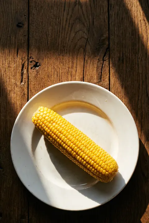 A plain boiled corn on the cob on a white plate