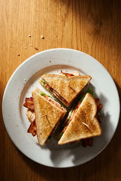 A club sandwich of three slices of toast with chicken on a white plate