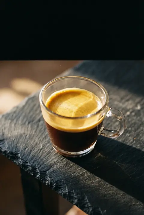 A single espresso with a thick golden crema in a clear glass cup