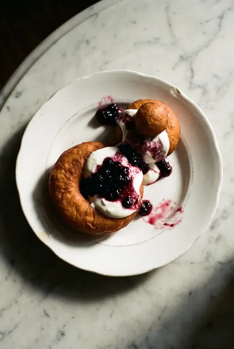 Two papanasi doughnuts on a white plate